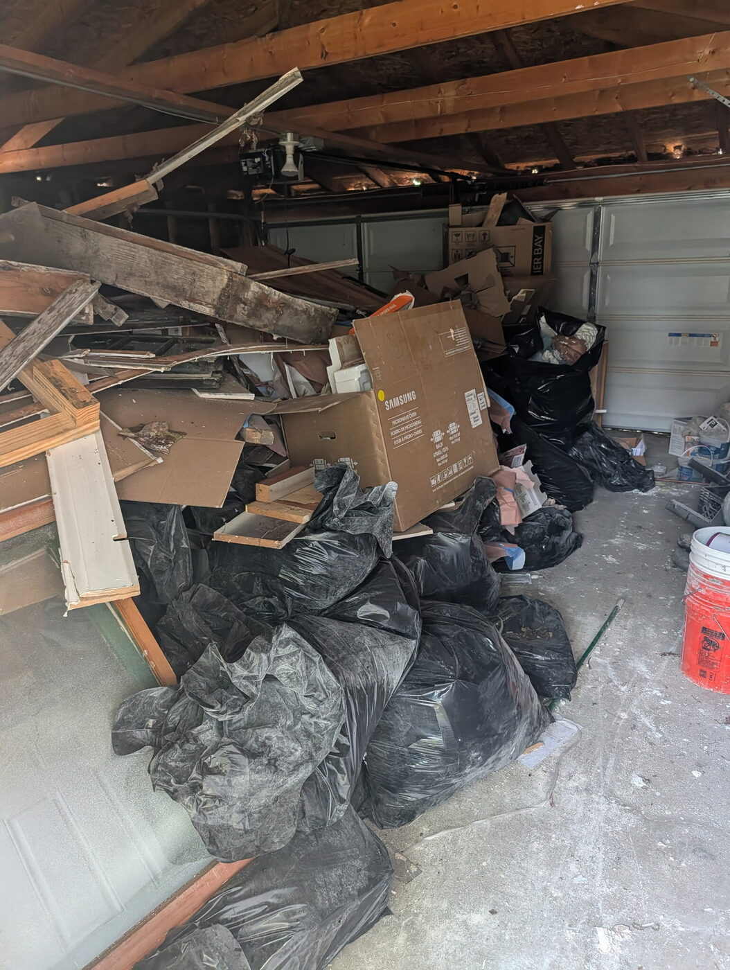 Garage filled with bags and construction debris before a JYD cleanout