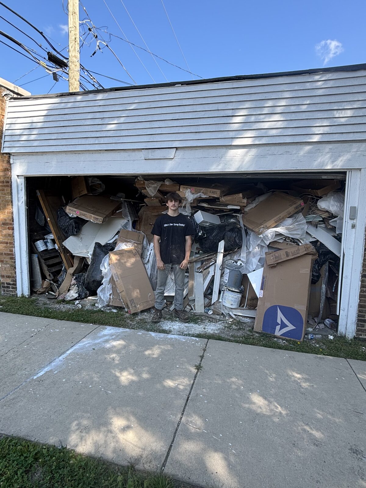 JYD Services crew member ready to clear an overflowing garage packed with cardboard and renovation debris