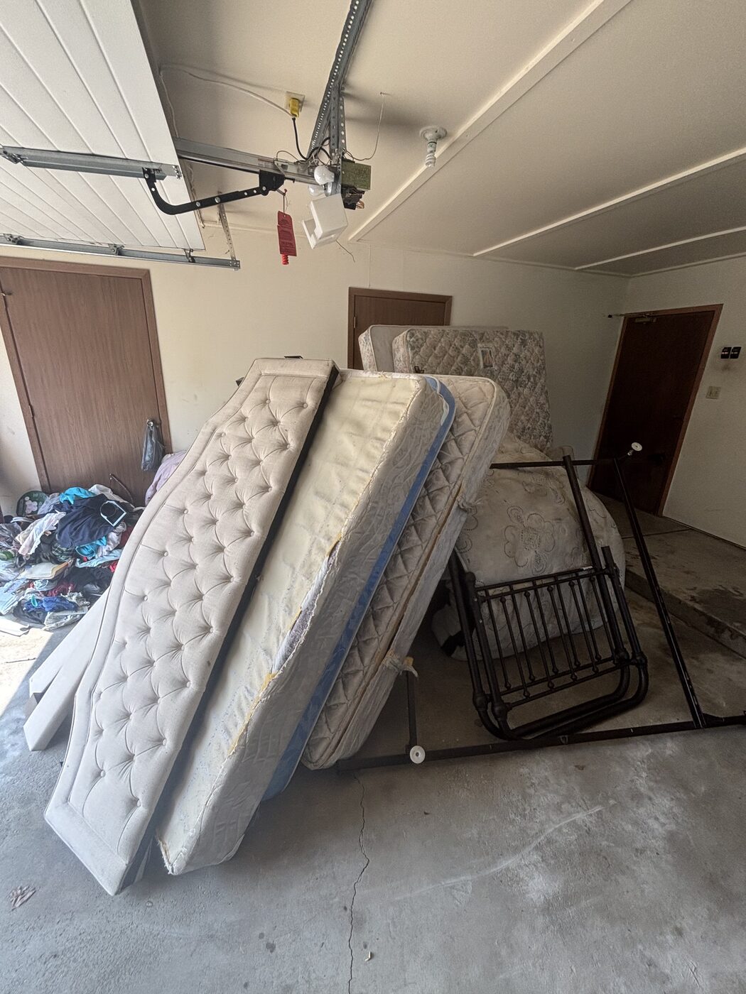 Mattresses and bed frame staged for pickup during a garage cleanout